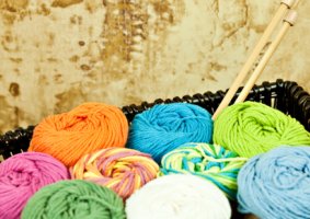 Image of a Yarn Stash in a woven basket with knitting needles